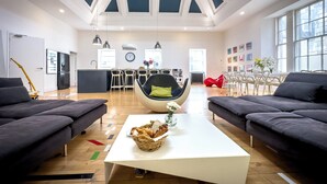 Amplia sala de estar con mobiliario moderno, una mesa de centro blanca y un alto techo con tragaluces.