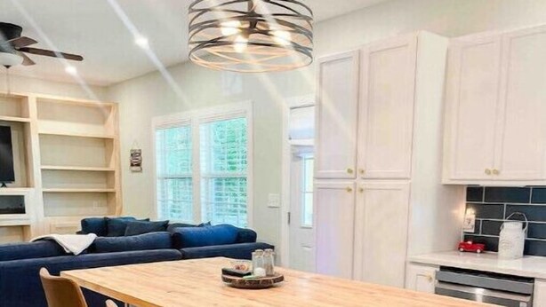 A modern kitchen with a wooden island, bar stools, and a stainless steel trash can. - Lakeview Oasis (Nevada)