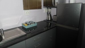 A kitchen with a sink, a microwave, a kettle, and a refrigerator. - Travelnest Tranquility Tiny Home (Johannesburg)
