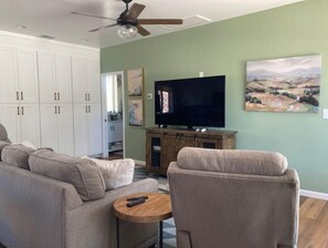 Relax in this stylish living room with a flat-screen TV, comfortable sofa, and a beautiful landscape painting.