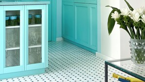 A teal-colored room with a glass cabinet, a door with a mirror, and a vase with white flowers. - Villa Sabrina by Elite Villas (Capri)