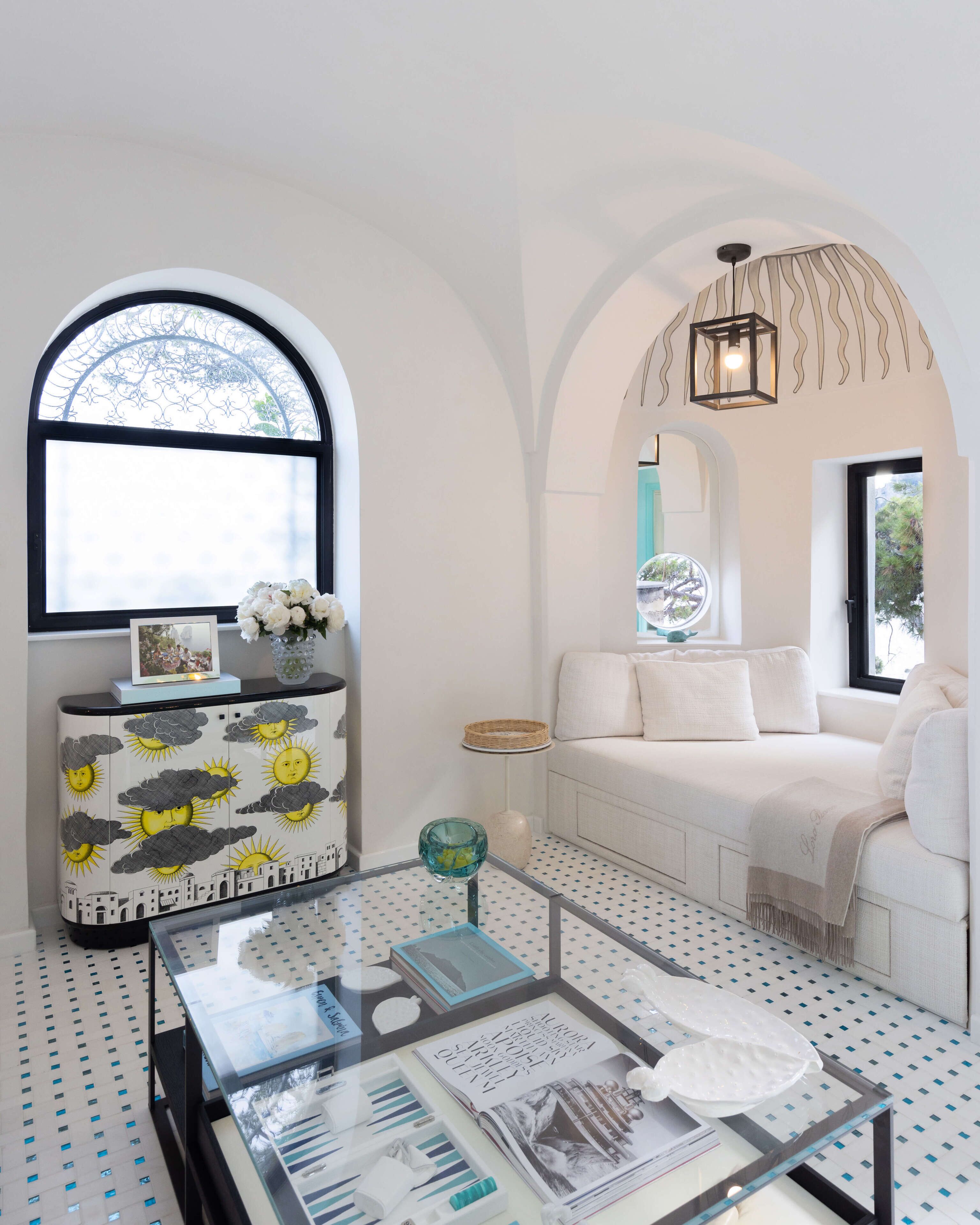 A modern living room with a glass coffee table, white sofa, and a decorative cabinet with a cityscape design.