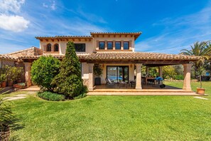 A two-story house with a patio area, a covered seating area, and a well-maintained lawn. - VILLA CAL MOLINER  with private pool. (Pollensa)