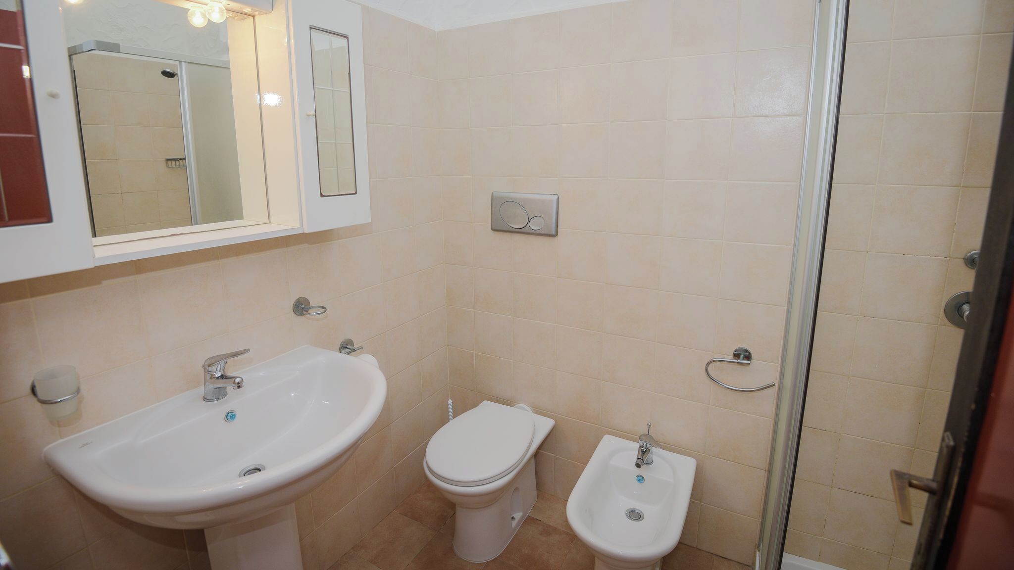 Une salle de bain équipée d’un lavabo, de toilettes, d’un bidet et d’une douche à parois en verre.