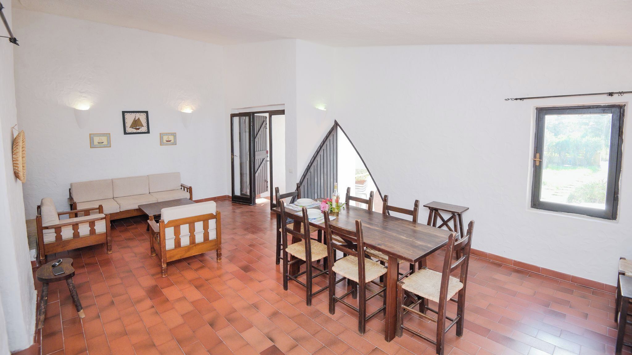 Ein geräumiges Zimmer mit einem Holzespeisetisch, einer Couch und einer Treppe, die in eine obere Ebene führt.