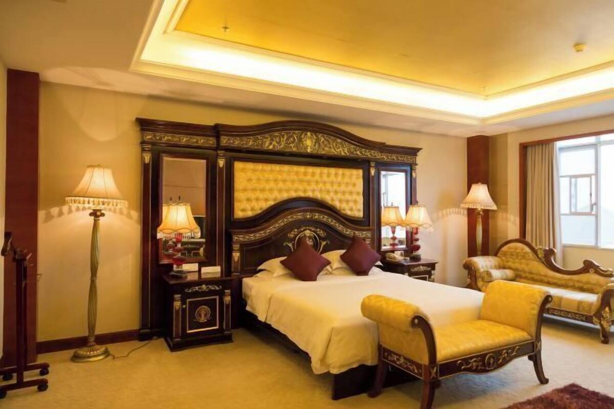 A bedroom with a large bed, two bedside tables, a chair, and a lamp.