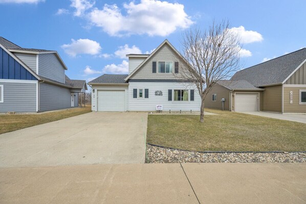 A residential neighborhood with single-family homes, a clear sky, and a well-maintained lawn.