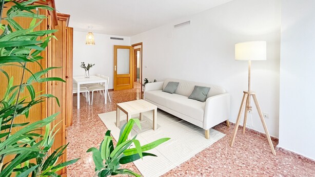 A modern living room with a white sofa, a dining table, and a floor lamp.