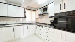Eine Küche mit weißen Schränken, einem schwarzen Backofen und einer Kaffeemaschine.