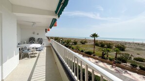 Ein Balkon mit Blick auf den Strand, einem Tisch mit Stühlen und einem Geländer.