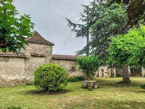 A courtyard with a stone building, a small tree, and a bush. - Petit Est Eco Cottage in large private garden near Saint-Émilion (Blasimon)
