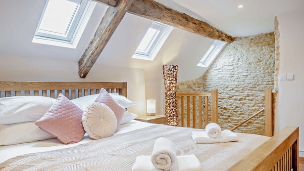 A bedroom with a wooden headboard, a stone wall, and skylights.
