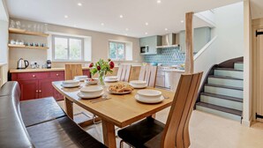 A modern kitchen with a dining area, wooden furniture, and a staircase.