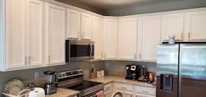 A modern kitchen with white cabinets, stainless steel appliances, and granite countertops.