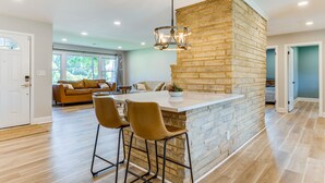 A modern kitchen with a central island, bar stools, and a hanging light fixture. - Charming Charlotte Home: 2 Mi to Downtown! (Charlotte)
