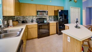Una cocina con armarios de madera, microondas, estufa y refrigerador.