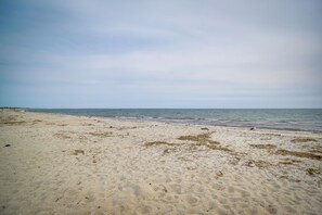 En sandstrand med blide bølger og en overskyet himmel.