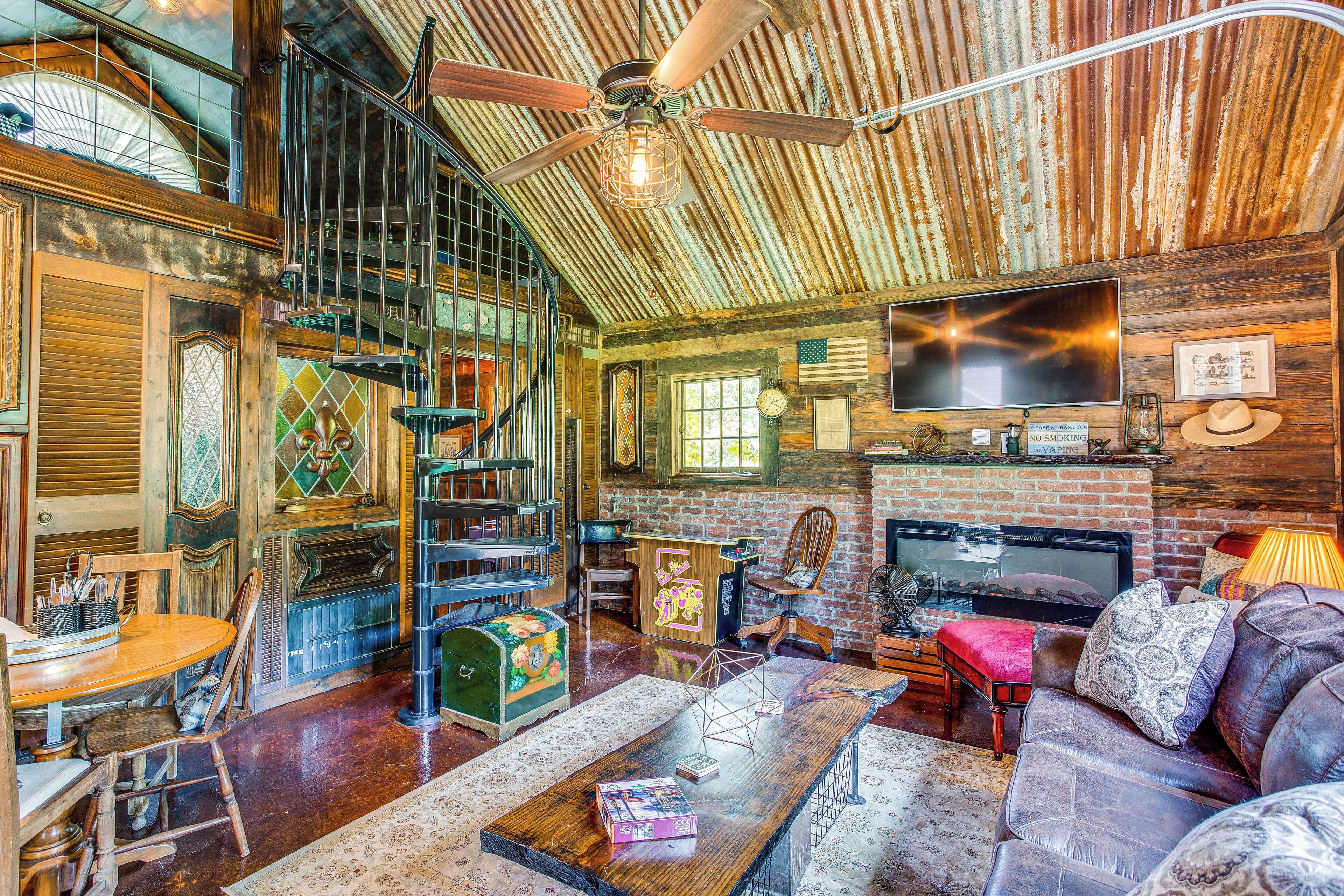 A rustic interior with a wooden ceiling, a fireplace, a television, and a dining area with a table and chairs.