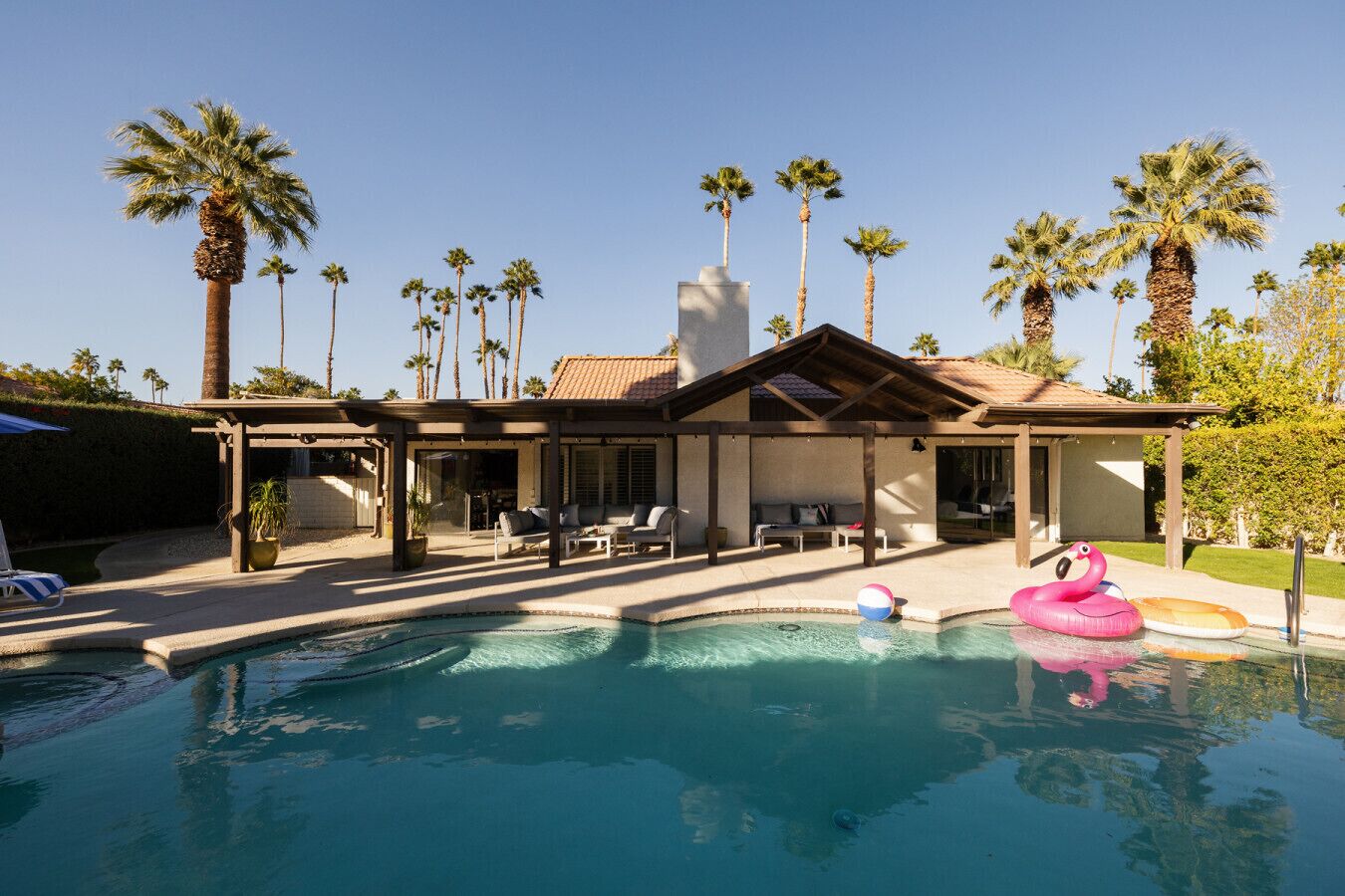 A pool area with lounge chairs and a covered seating area.