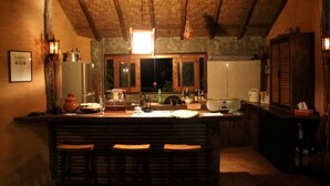 Una cucina rustica con soffitto in legno, una zona bar con sgabelli e diversi elettrodomestici e utensili sul piano di lavoro.
