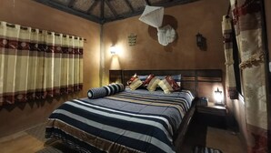 Una camera da letto con una coperta a righe, un soffitto in legno e una luce notturna.