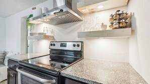 Een moderne keuken met een roestvrijstalen fornuis, granieten aanrecht en een ingebouwde oven.