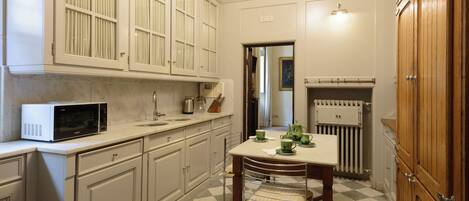 A kitchen with white cabinets, a microwave, a sink, and a radiator.