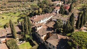 A traditional villa with a courtyard, surrounded by lush greenery and hills.