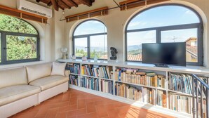 A cozy reading nook with a sofa, a large window, and a bookshelf filled with books.