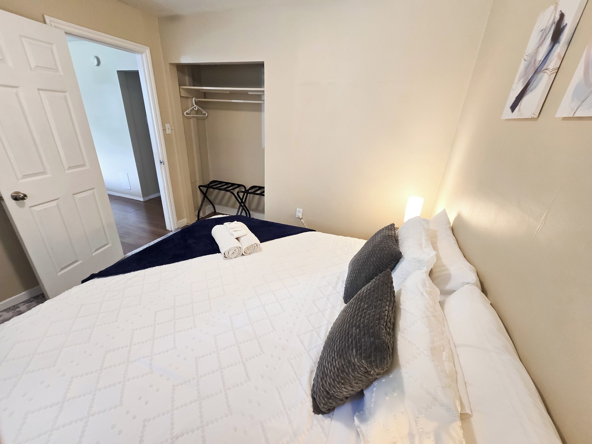 Un dormitorio con cama, perchero y puerta que da a otra habitación.