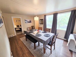 A dining area with a table set for four, a bench, and a window with curtains. - Family House with Httb Playgr BBQ Firept (Calgary)