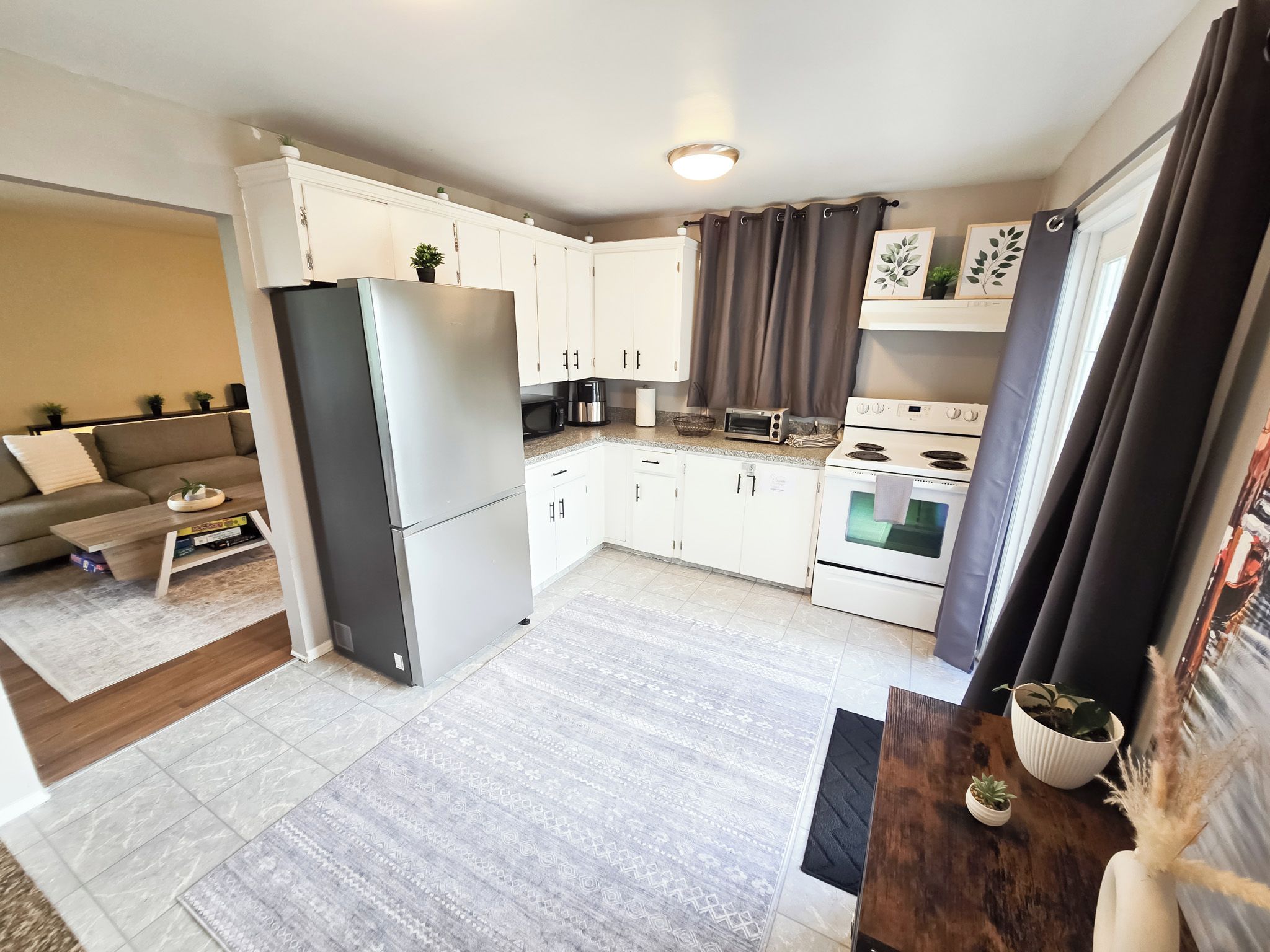 A compact kitchen with white cabinets, a refrigerator, a stove, and a microwave.