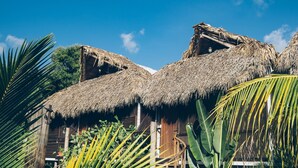 Uma construção tradicional com telhado de colmo, paredes de madeira e escada de madeira que leva a um andar superior.