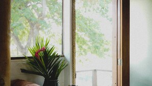Um banco de madeira com toalhas e um vaso de planta perto de uma janela com vista para árvores.