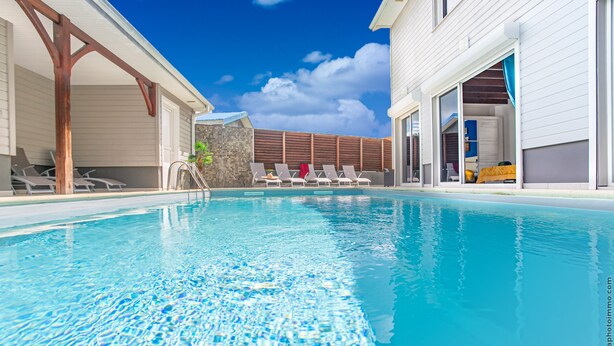 A swimming pool with lounge chairs and a covered area.