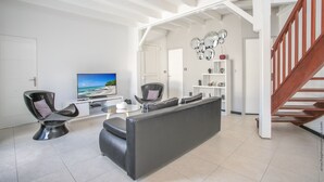 A modern living room with a sofa, a TV, and a staircase.