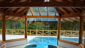 Una terraza de madera con un jacuzzi y vista a un área boscosa.