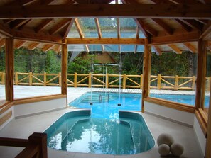 Una piscina cubierta, una piscina al aire libre, tumbonas