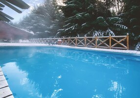 Una piscina azul cristalina con una terraza de madera y una valla de madera.