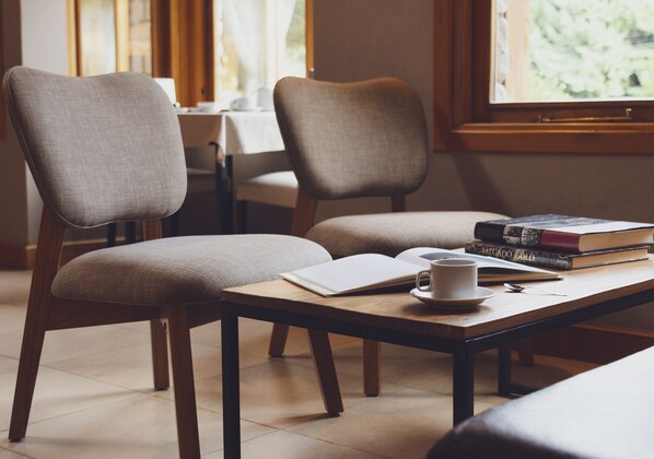 A cozy seating area with two chairs and a table, a cup, a book, and a notebook.