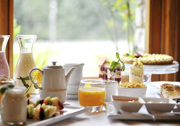 A breakfast table with various food items and drinks, including a pitcher, a glass of orange juice, and a plate of toast.
