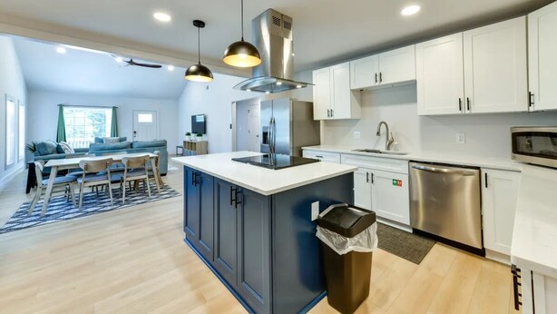 Una cocina moderna con armarios blancos, electrodomésticos de acero inoxidable y una isla central.