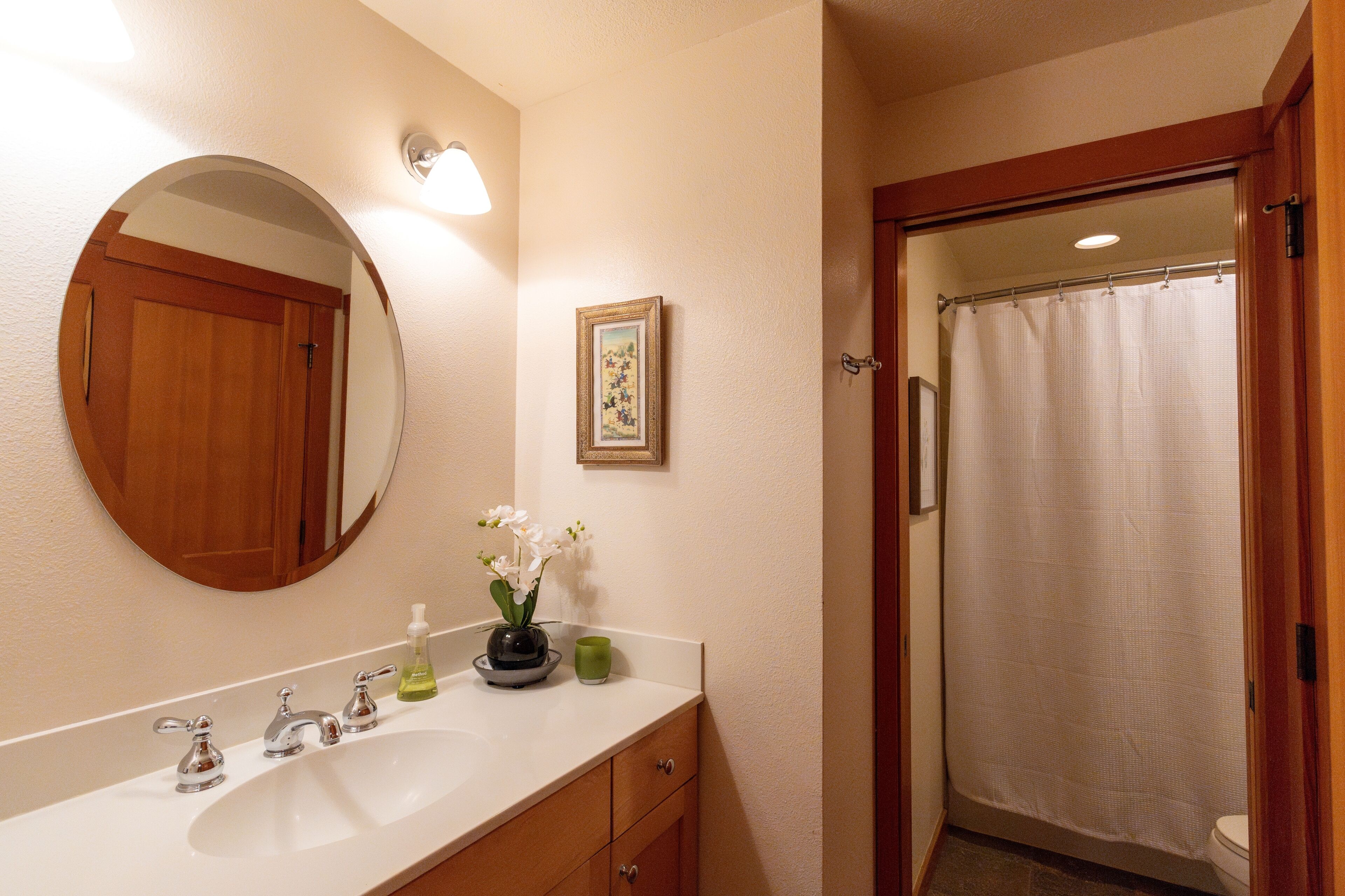 Une salle de bain avec un lavabo, un miroir et un rideau de douche.