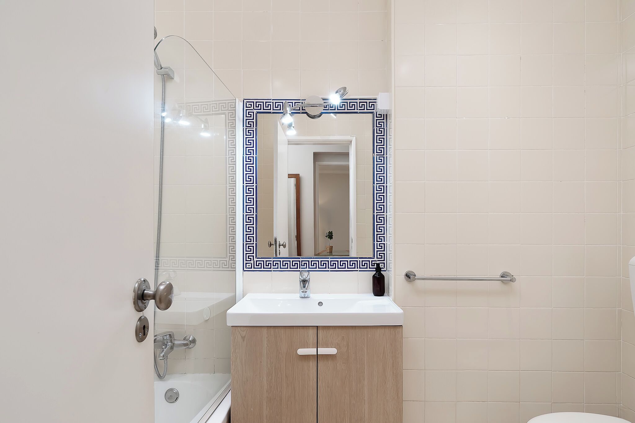 A bathroom with a white sink, wooden cabinet, and a mirror with a decorative frame.