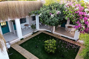 A courtyard with a thatched roof, white walls, and outdoor seating.