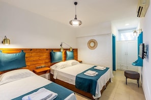 A hotel room with two beds, wooden headboards, a round mirror, a bench, and a wardrobe.