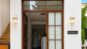 A modern house entrance with a wooden staircase, a kitchen visible through the door, and a sign reading 'Resepsiyon'. - Avlu Butik Otel Palamutbükü (Datça)