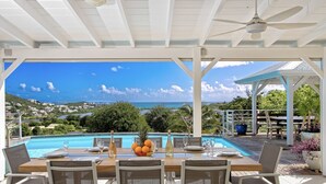 An outdoor dining area with a pool view, white furniture, and a ceiling fan. - Villa Eskarcel, très spacieuse, vue mer sur Orient Bay, 4 chambres (Mont Vernon)