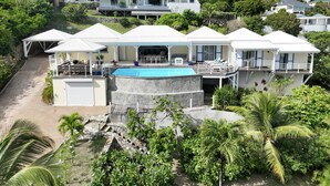 A hillside property with multiple white houses, a central pool, and lush greenery. - Villa Eskarcel, très spacieuse, vue mer sur Orient Bay, 4 chambres (Mont Vernon)