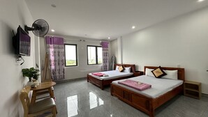 A hotel room with two beds, a desk, a chair, a TV, and a ceiling fan. - Ha Thu Motel (Da Nang)